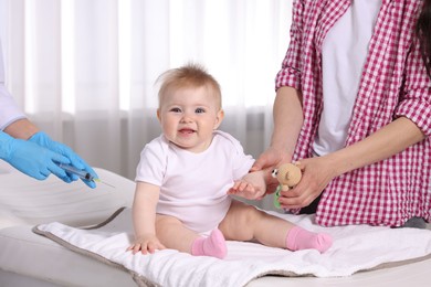 Photo of Mother and her cute baby having appointment with pediatrician in clinic, closeup. Doctor vaccinating child