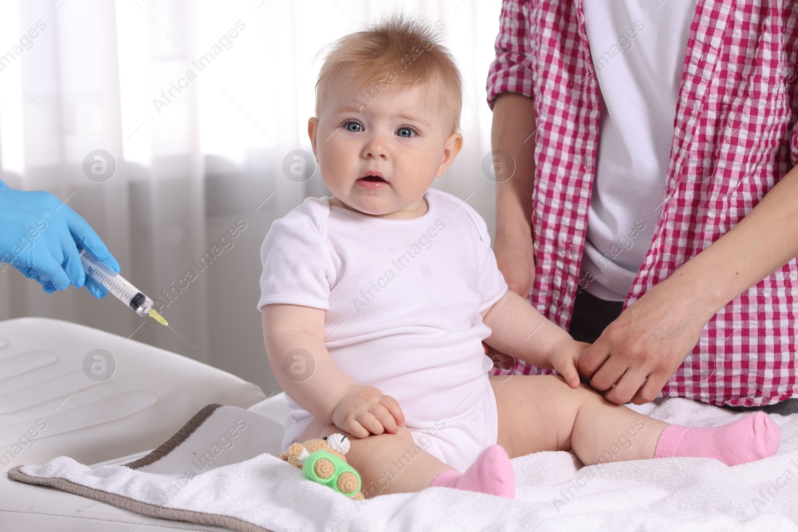 Mother and her cute baby having appointment with pediatrician in clinic, closeup. Doctor vaccinating child Photo of Mother and her cute baby having appointment with pediatrician in clinic, closeup. Doctor vaccinating child