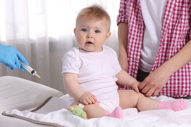 Photo of Mother and her cute baby having appointment with pediatrician in clinic, closeup. Doctor vaccinating child