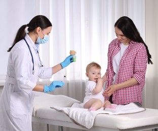 Photo of Mother and her cute baby having appointment with pediatrician in clinic. Doctor vaccinating child