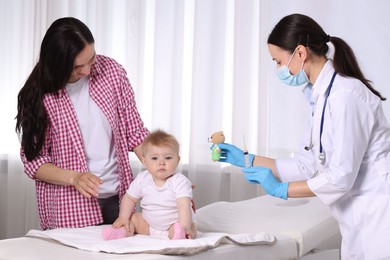 Photo of Mother and her cute baby having appointment with pediatrician in clinic. Doctor vaccinating child