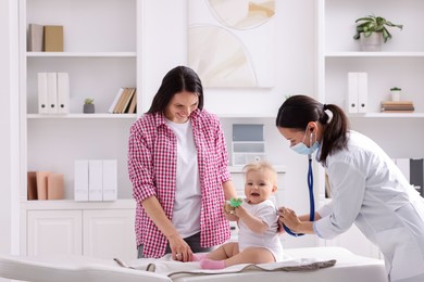 Photo of Pediatrician examining baby with stethoscope in clinic