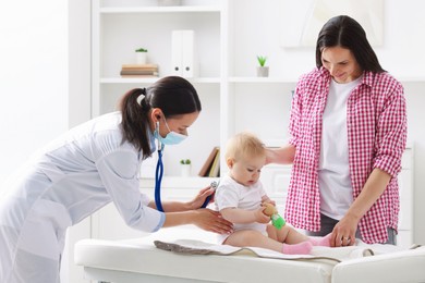 Photo of Pediatrician examining baby with stethoscope in clinic