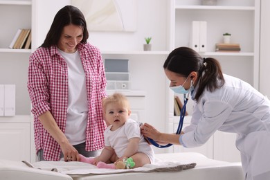Photo of Pediatrician examining baby with stethoscope in clinic