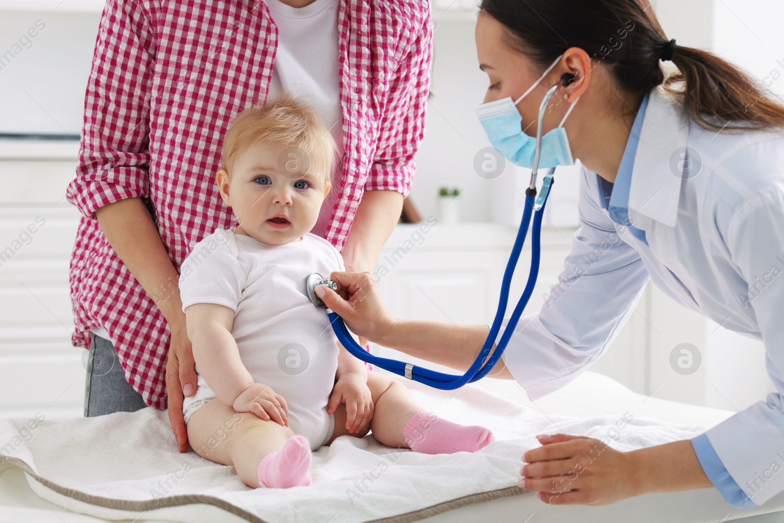 Pediatrician examining baby with stethoscope in clinic Photo of Pediatrician examining baby with stethoscope in clinic