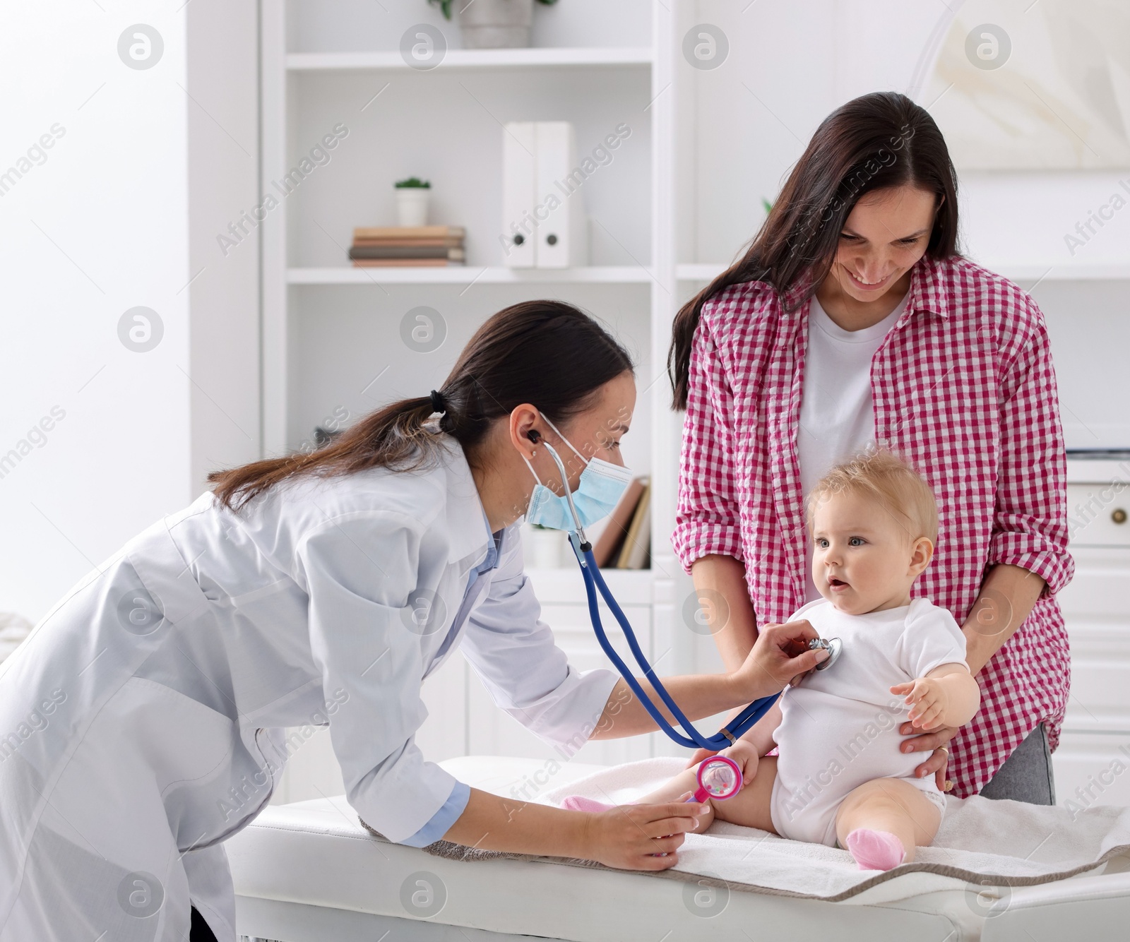 Pediatrician examining baby with stethoscope in clinic Photo of Pediatrician examining baby with stethoscope in clinic