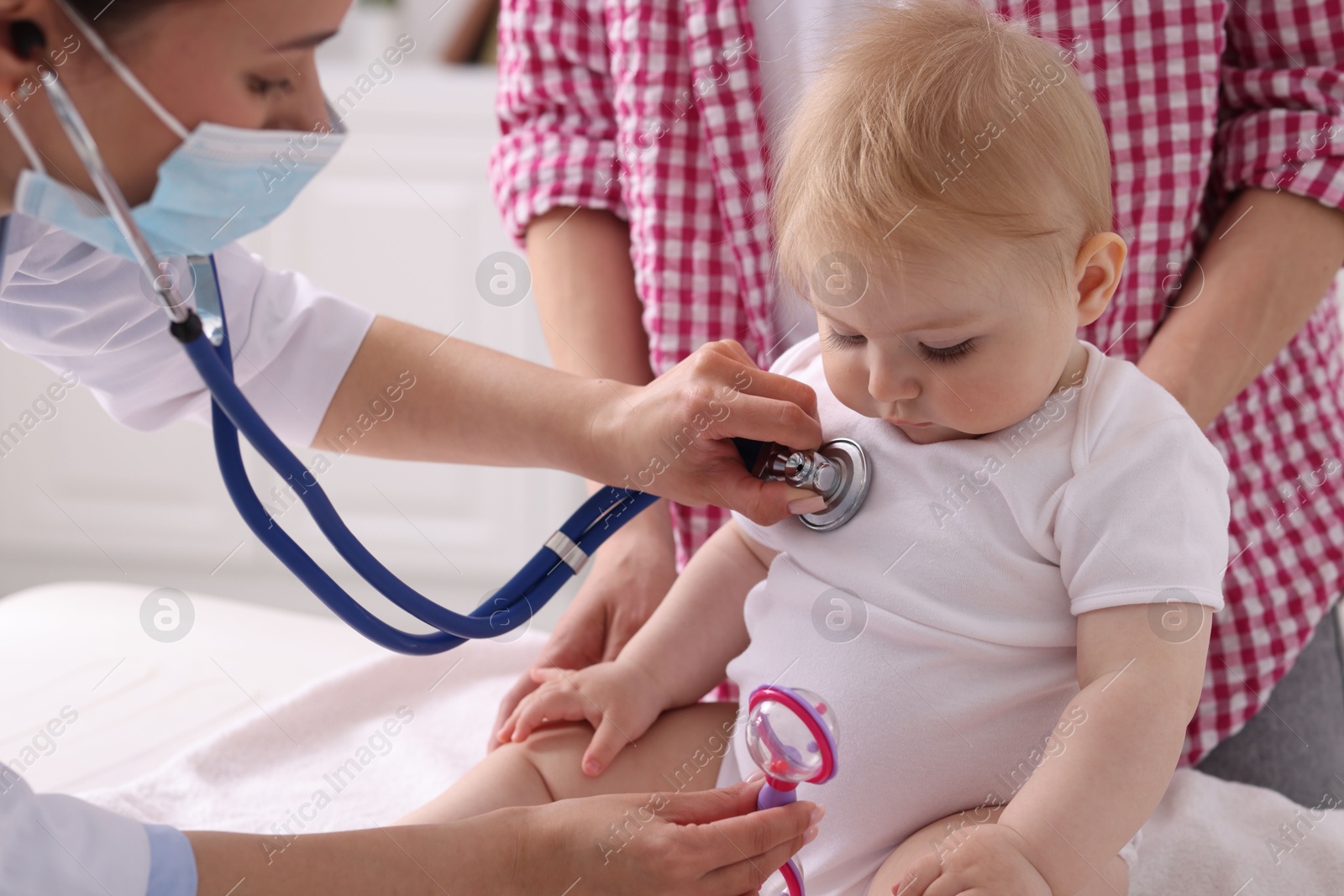 Pediatrician examining baby with stethoscope in clinic, closeup Photo of Pediatrician examining baby with stethoscope in clinic, closeup