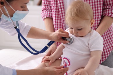 Photo of Pediatrician examining baby with stethoscope in clinic, closeup