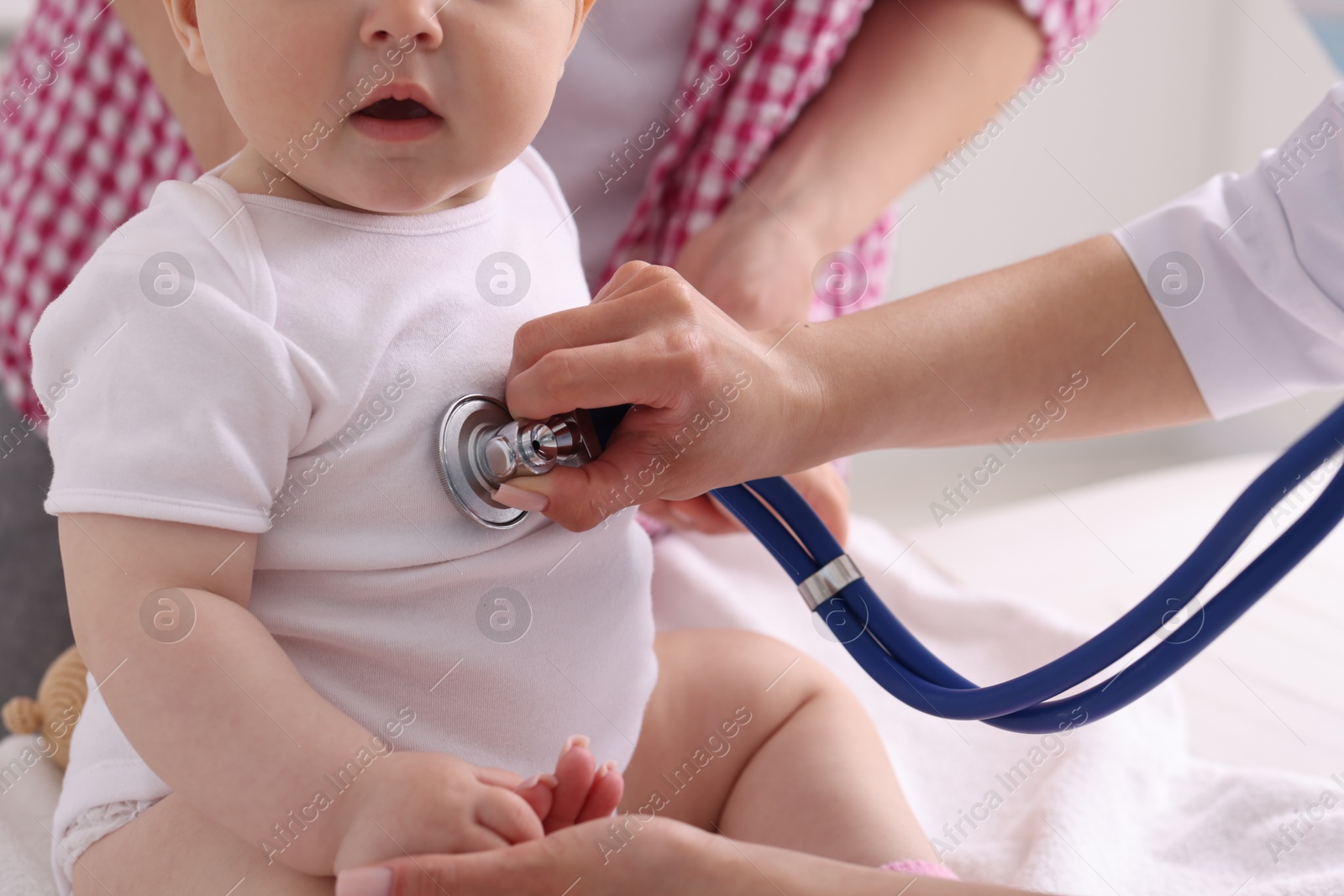 Pediatrician examining baby with stethoscope in clinic, closeup Photo of Pediatrician examining baby with stethoscope in clinic, closeup