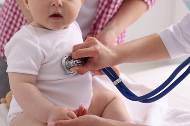 Photo of Pediatrician examining baby with stethoscope in clinic, closeup