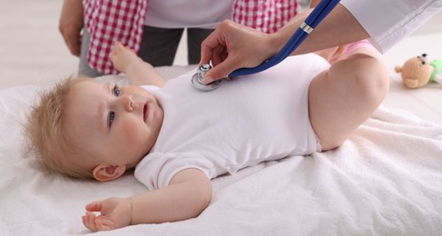 Photo of Pediatrician examining baby with stethoscope in clinic, closeup
