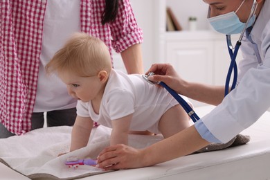 Photo of Pediatrician examining baby with stethoscope in clinic, closeup