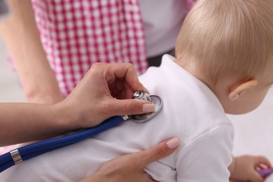 Photo of Pediatrician examining baby with stethoscope in clinic, closeup