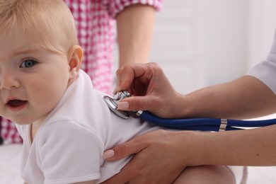 Photo of Pediatrician examining baby with stethoscope in clinic, closeup