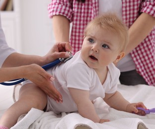 Photo of Pediatrician examining baby with stethoscope in clinic, closeup