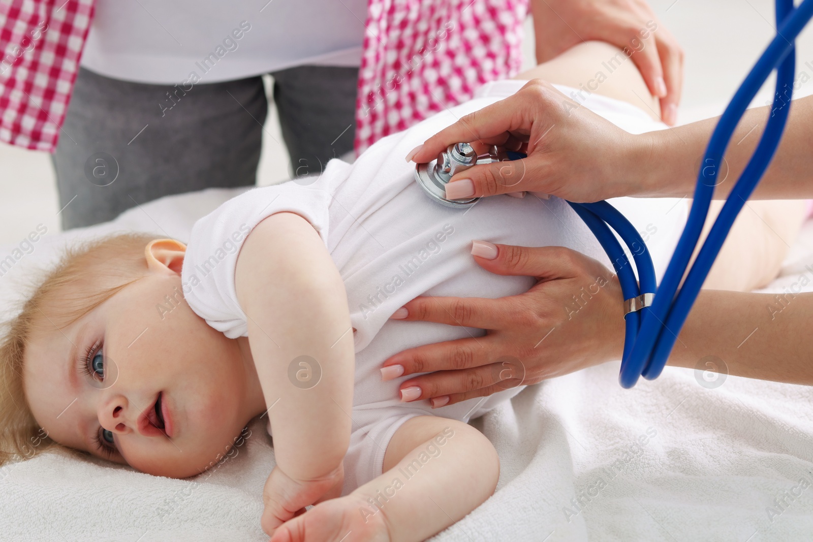 Pediatrician examining baby with stethoscope in clinic, closeup Photo of Pediatrician examining baby with stethoscope in clinic, closeup
