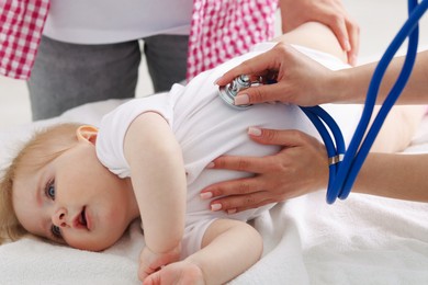 Photo of Pediatrician examining baby with stethoscope in clinic, closeup