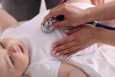 Photo of Pediatrician examining baby with stethoscope in clinic, closeup