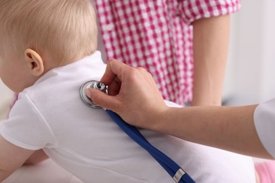 Photo of Pediatrician examining baby with stethoscope in clinic, closeup