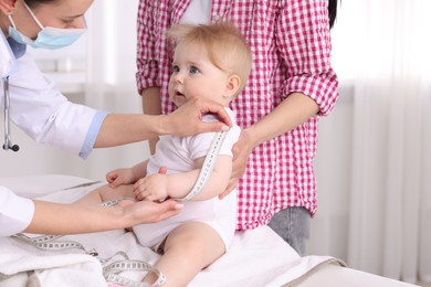 Photo of Pediatrician measuring little baby's arm in clinic, closeup