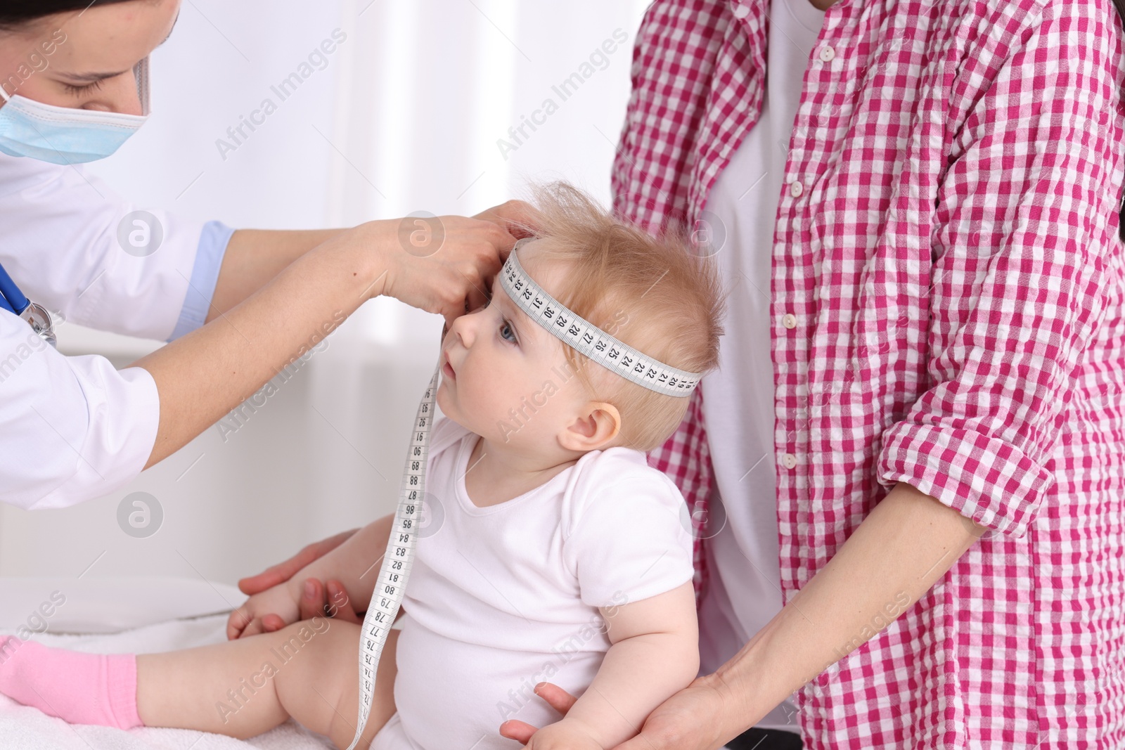 Pediatrician measuring little baby's head in clinic, closeup Photo of Pediatrician measuring little baby's head in clinic, closeup