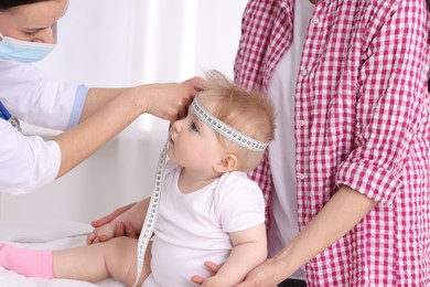 Photo of Pediatrician measuring little baby's head in clinic, closeup