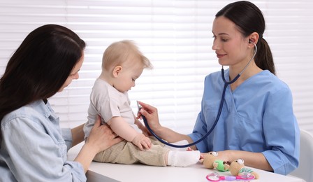 Photo of Pediatrician examining baby with stethoscope in clinic