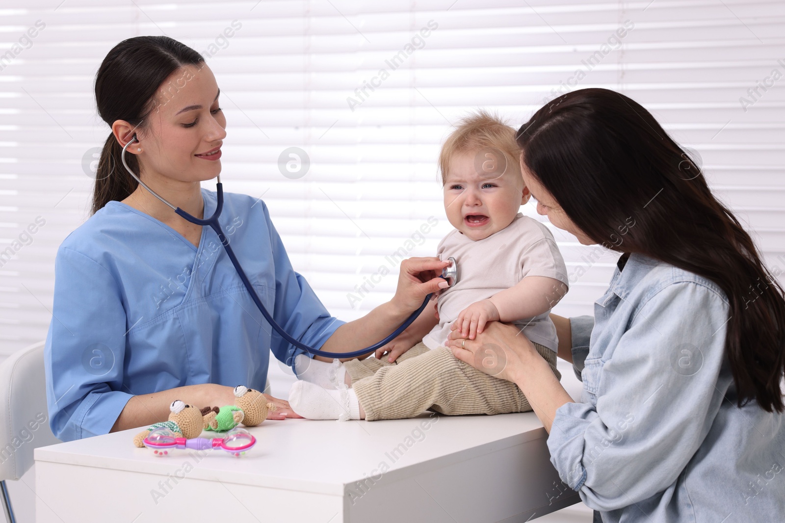 Pediatrician examining baby with stethoscope in clinic Photo of Pediatrician examining baby with stethoscope in clinic