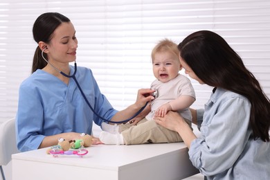 Photo of Pediatrician examining baby with stethoscope in clinic