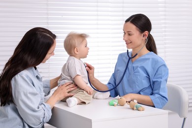 Photo of Pediatrician examining baby with stethoscope in clinic