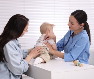 Photo of Pediatrician examining baby with stethoscope in clinic