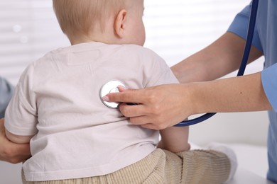 Photo of Pediatrician examining baby with stethoscope in clinic, closeup