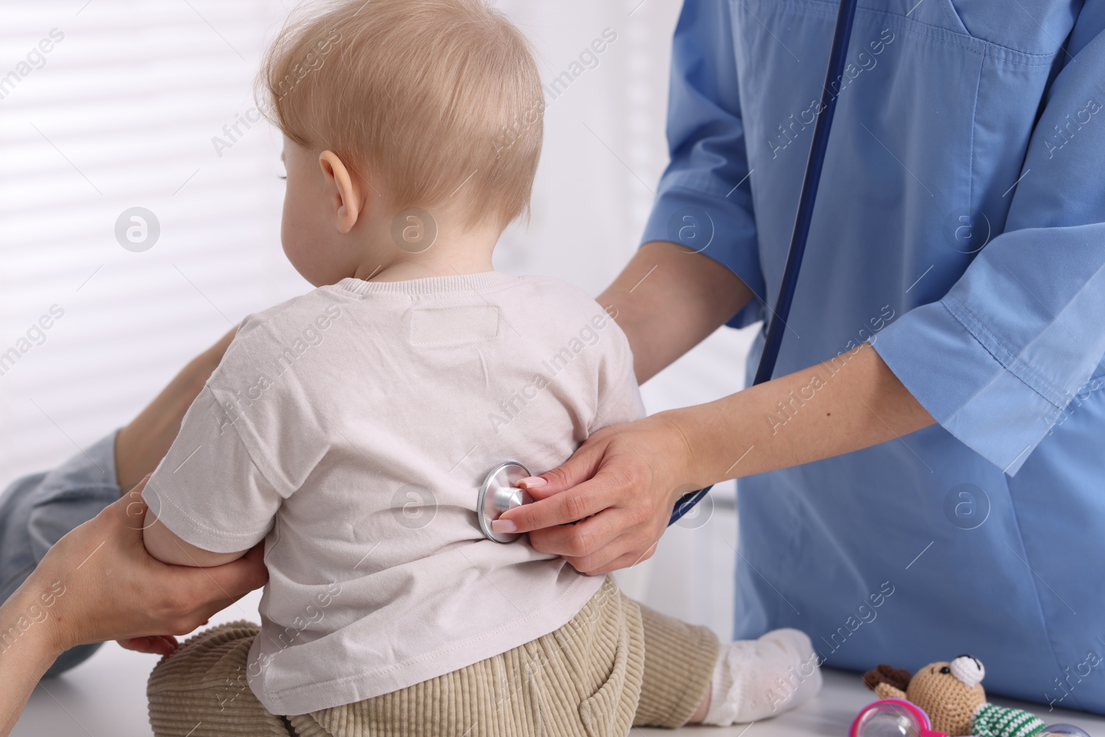 Pediatrician examining baby with stethoscope in clinic, closeup Photo of Pediatrician examining baby with stethoscope in clinic, closeup
