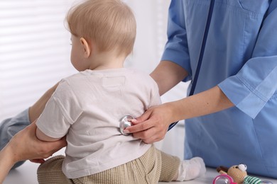 Photo of Pediatrician examining baby with stethoscope in clinic, closeup