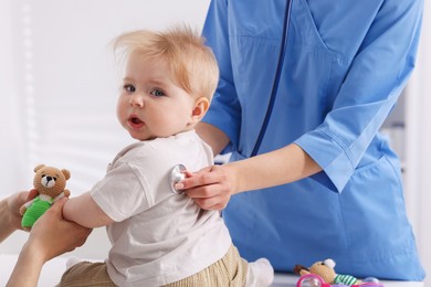 Photo of Pediatrician examining baby with stethoscope in clinic, closeup