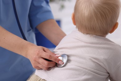 Photo of Pediatrician examining baby with stethoscope in clinic, closeup