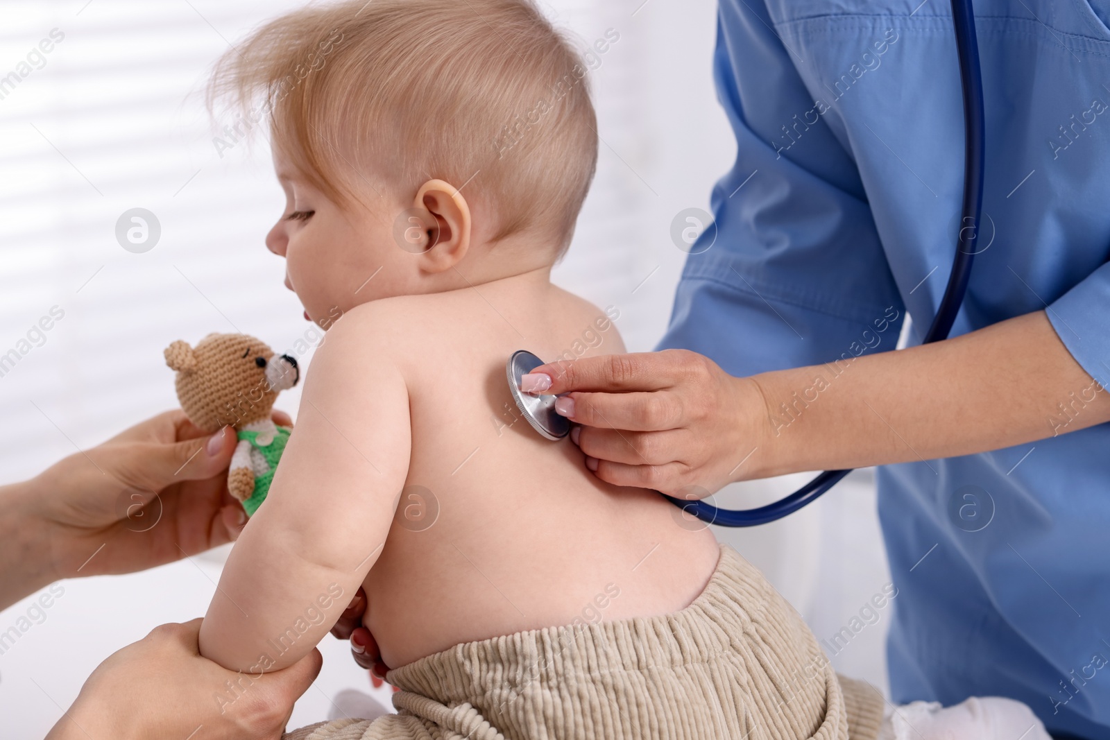 Pediatrician examining baby with stethoscope in clinic, closeup Photo of Pediatrician examining baby with stethoscope in clinic, closeup