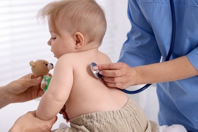 Photo of Pediatrician examining baby with stethoscope in clinic, closeup