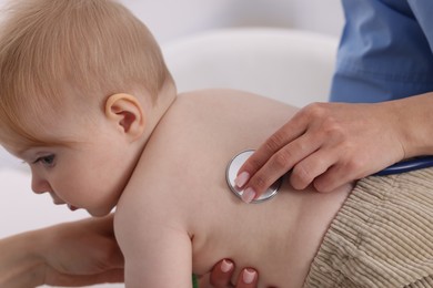 Photo of Pediatrician examining baby with stethoscope in clinic, closeup