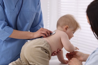 Photo of Pediatrician examining baby with stethoscope in clinic, closeup