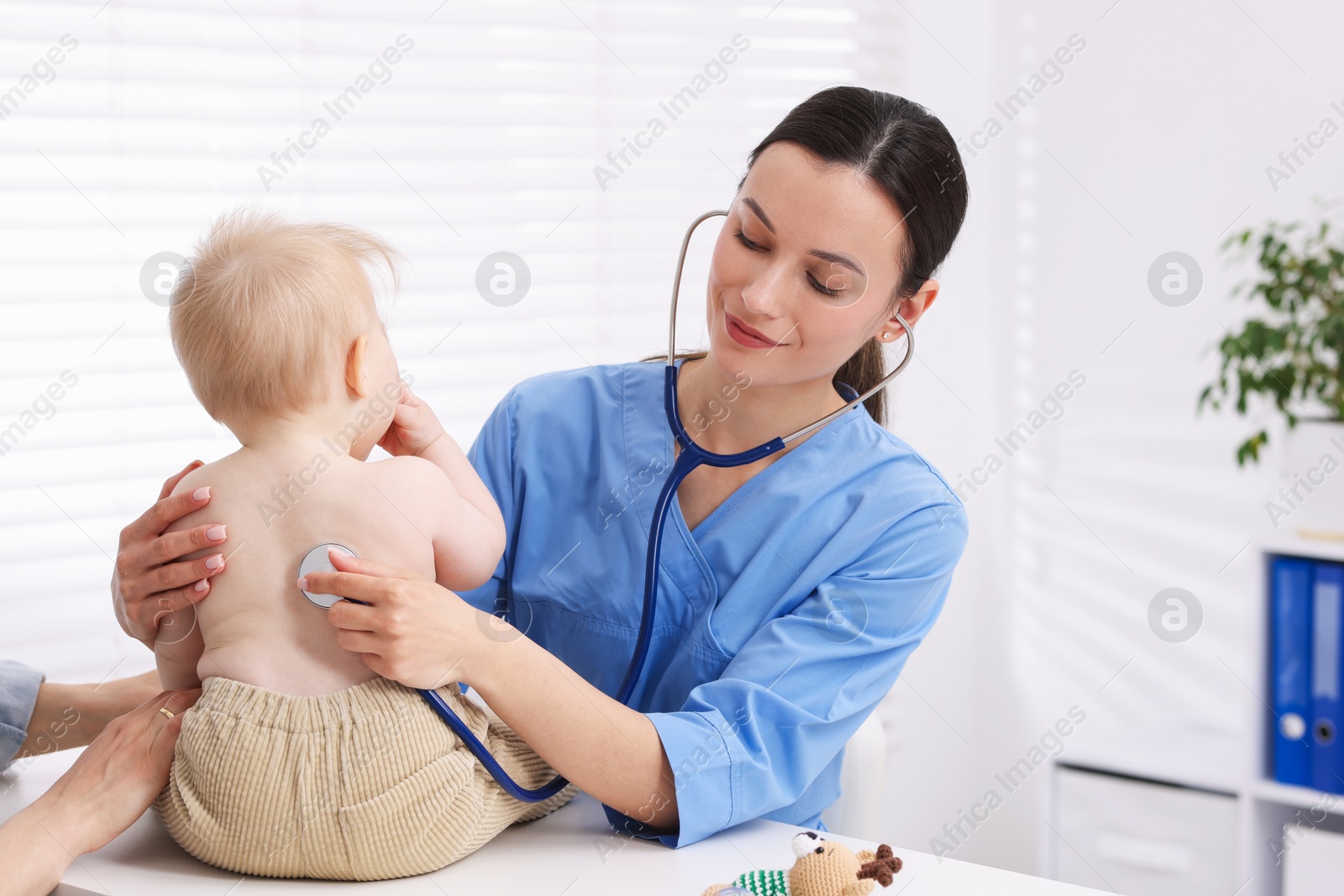 Pediatrician examining baby with stethoscope in clinic Photo of Pediatrician examining baby with stethoscope in clinic
