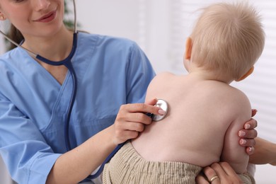 Photo of Pediatrician examining baby with stethoscope in clinic, closeup