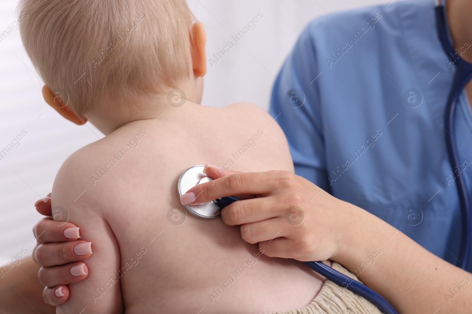 Pediatrician examining baby with stethoscope in clinic, closeup Photo of Pediatrician examining baby with stethoscope in clinic, closeup