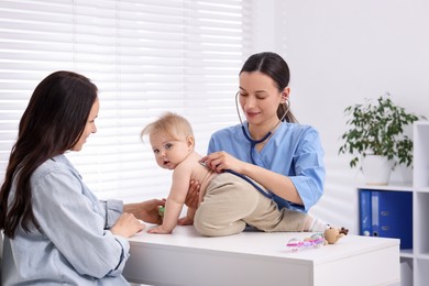 Photo of Pediatrician examining baby with stethoscope in clinic