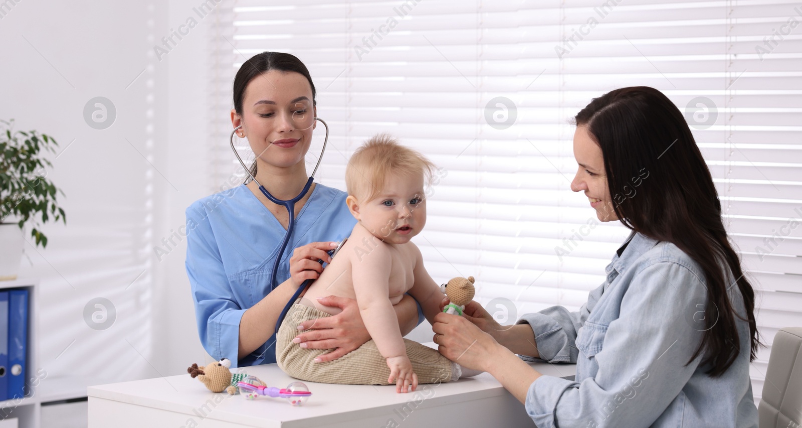 Pediatrician examining baby with stethoscope in clinic Photo of Pediatrician examining baby with stethoscope in clinic