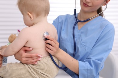 Photo of Pediatrician examining baby with stethoscope in clinic, closeup