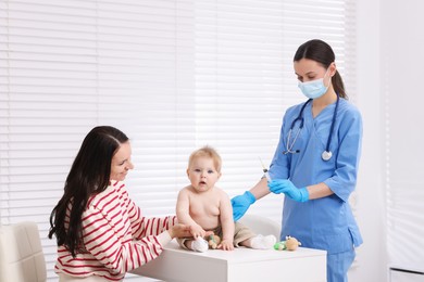 Photo of Mother and her cute baby having appointment with pediatrician in clinic. Doctor vaccinating child