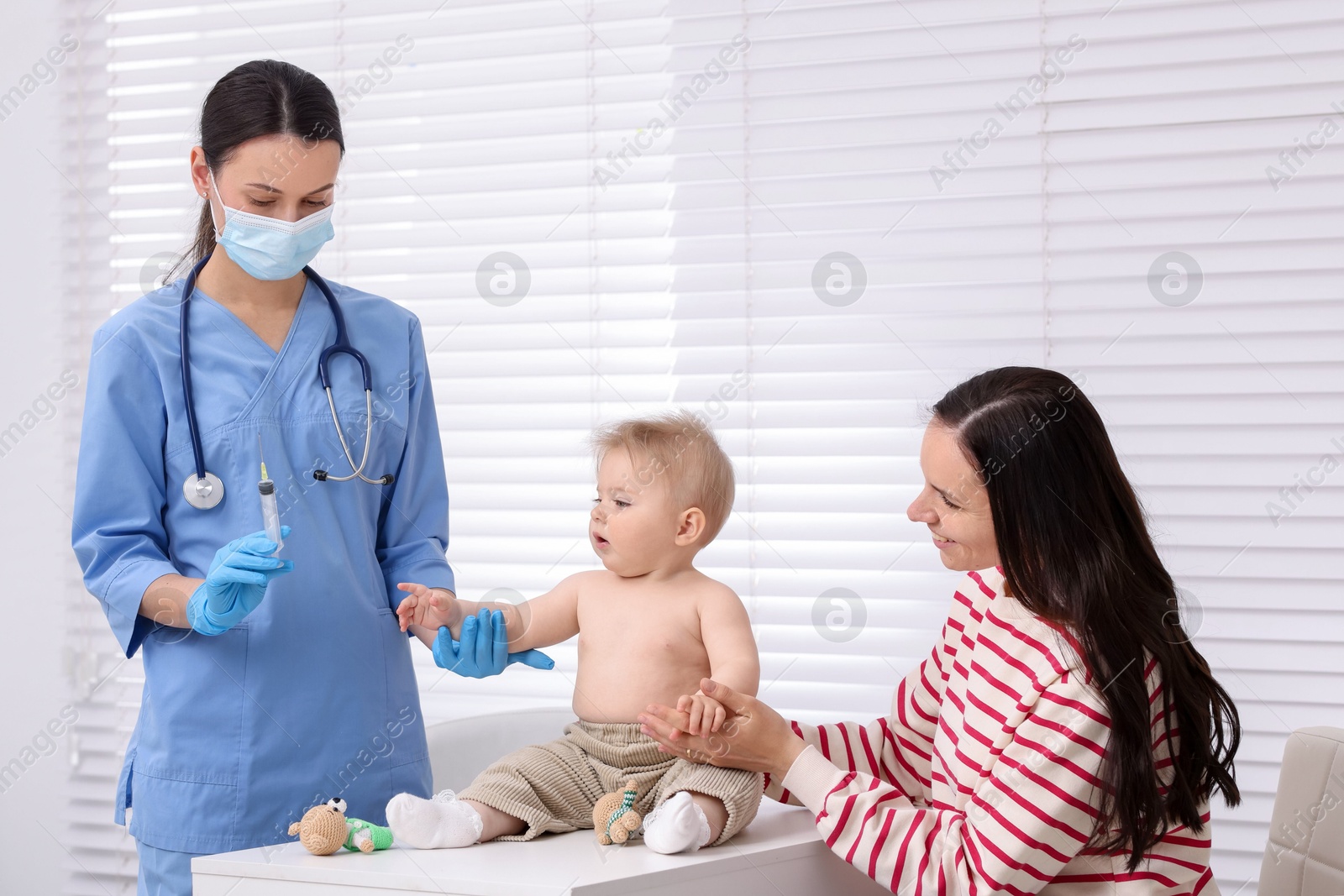 Mother and her cute baby having appointment with pediatrician in clinic. Doctor vaccinating child Photo of Mother and her cute baby having appointment with pediatrician in clinic. Doctor vaccinating child