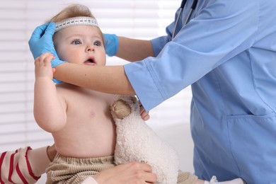 Photo of Pediatrician measuring little baby's head in clinic, closeup