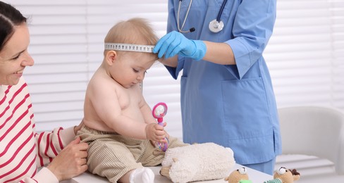 Photo of Pediatrician measuring little baby's head in clinic